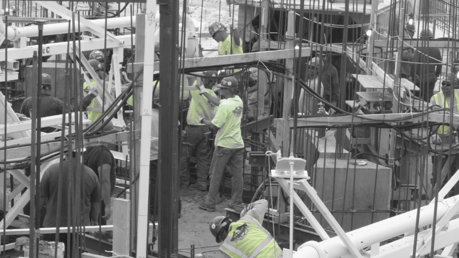 Crew of men in hard hats and neon shirts working on a construction site.
