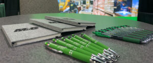 Tradeshow table with notebook and pens with McC logo