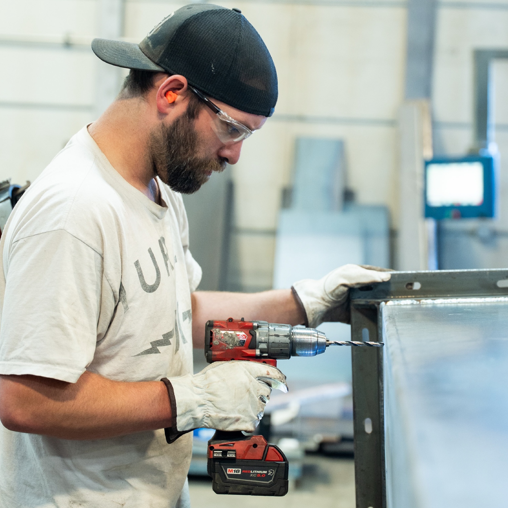 Shop worker drilling into steel
